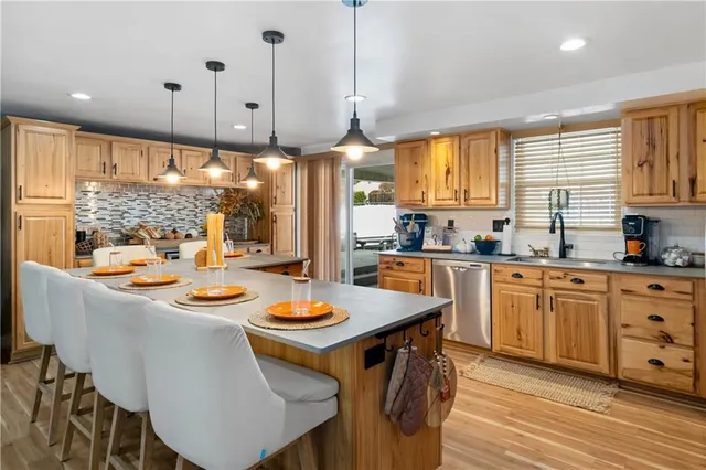 a kitchen with a stove a sink a center island and a wooden floor