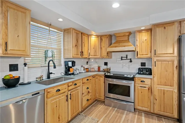 a open kitchen with stainless steel appliances granite countertop a stove a refrigerator a sink dishwasher with a dining table and chairs with wooden floor