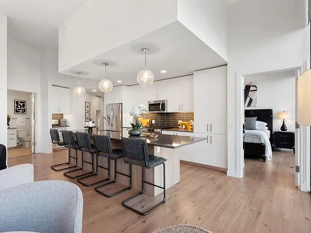 a living room with furniture kitchen view and a chandelier