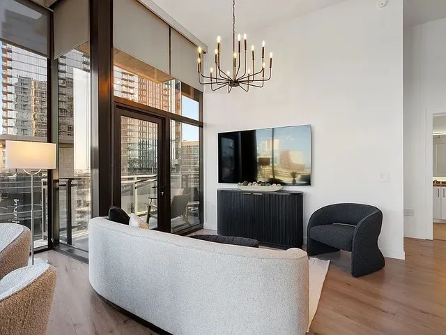 a living room with furniture kitchen area and a large window