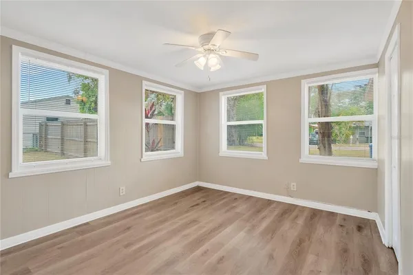 a view of an empty room with wooden floor and a window