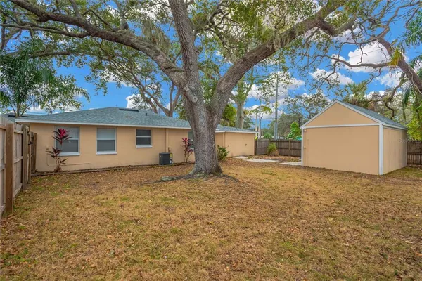 a backyard of a house with large trees and brick wall