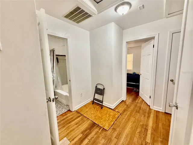 a view of a bedroom with a bed and wooden floor