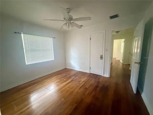 a view of empty room with wooden floor and fan