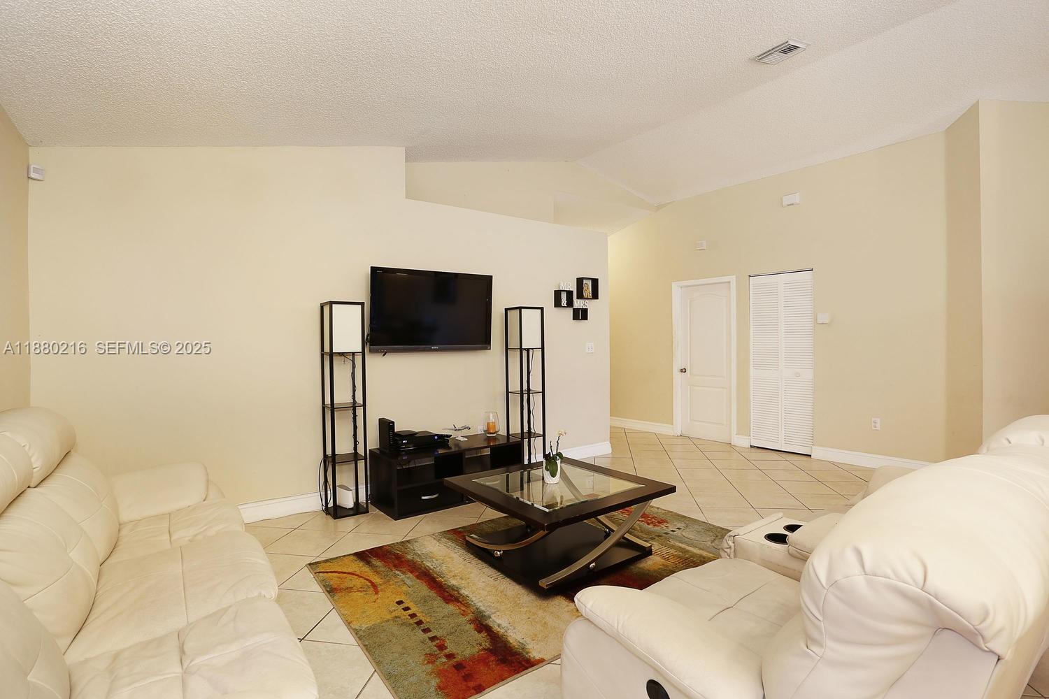 14285 Southwest 176th Terrace Miami, FL 33177 - Photo 4 of 20 a living room with a couch and a flat screen tv