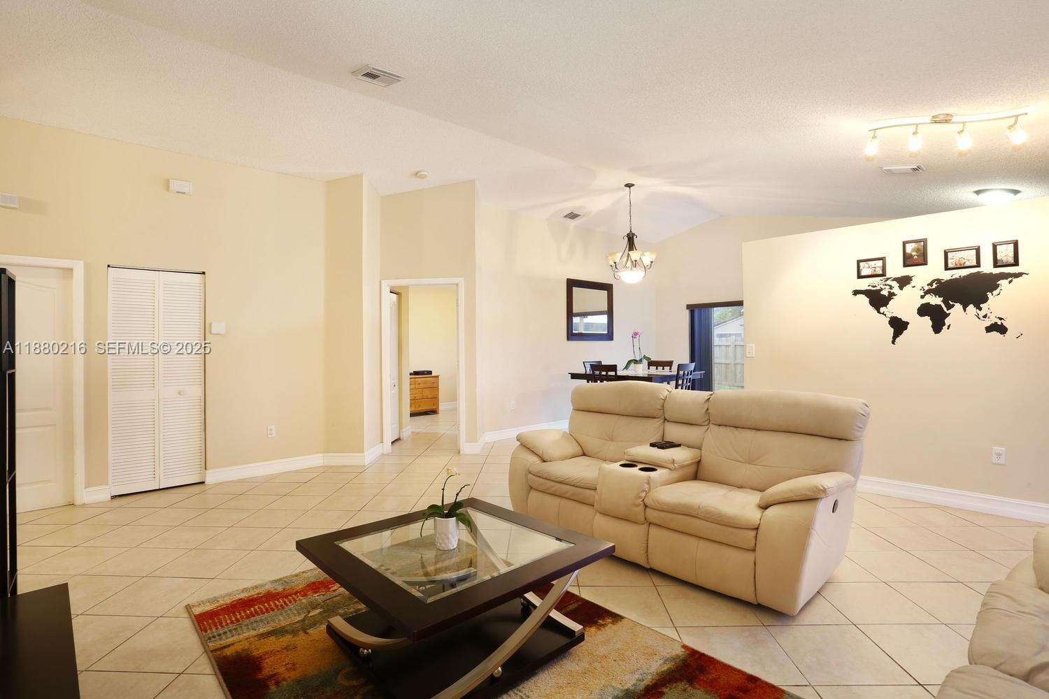14285 Southwest 176th Terrace Miami, FL 33177 - Photo 6 of 20 a living room with furniture and a chandelier