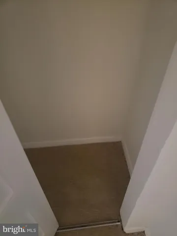 an empty room with a chandelier fan and windows