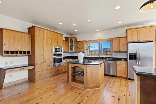 a kitchen with stainless steel appliances granite countertop a refrigerator a stove top oven and a sink with cabinets