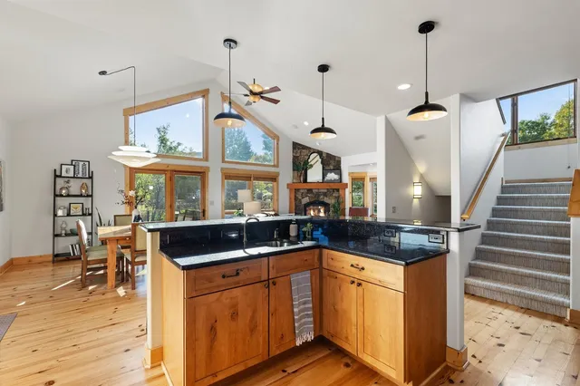 a kitchen with granite countertop a stove a sink a dining table and chairs with wooden floor