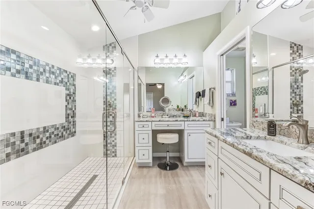 a spacious bathroom with a granite countertop sink a toilet a mirror and shower