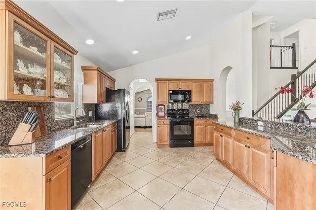 a large kitchen with stainless steel appliances kitchen island granite countertop a refrigerator and stove