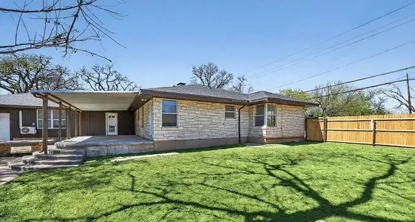 a view of an empty room with wooden floor fireplace and a window