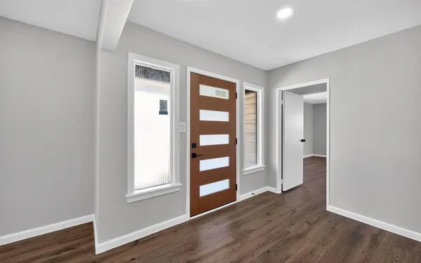 a view of an empty room with a window and wooden floor