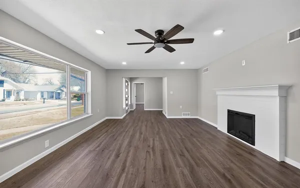 a view of an empty room with window and wooden floor