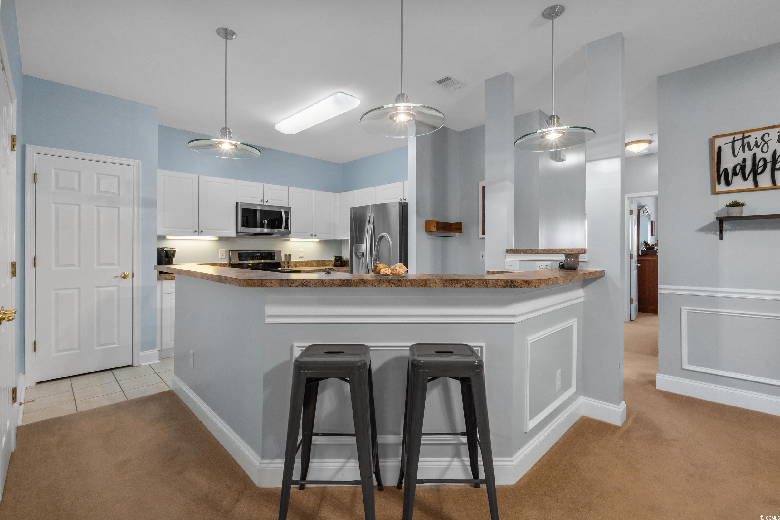 70 Addison Cottage Way, Unit 322 Murrells Inlet, SC 29576 - Photo 10 of 40 Kitchen with pendant lighting, white cabinets, a kitchen breakfast bar, and light colored carpet