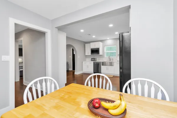 a kitchen with stainless steel appliances kitchen island granite countertop a dining table chairs and a refrigerator