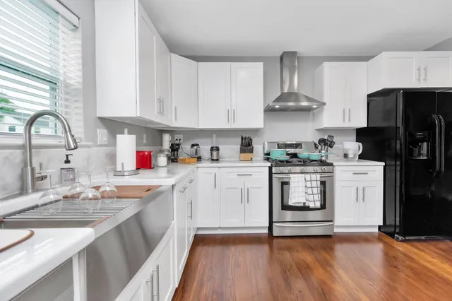 a kitchen with a sink white cabinets and stainless steel appliances