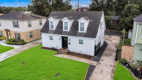 a view of a white house next to a yard with big trees