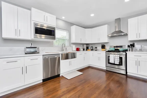 a kitchen with cabinets stainless steel appliances and wooden floor