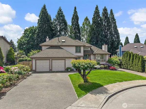 a front view of a house with a garden and trees