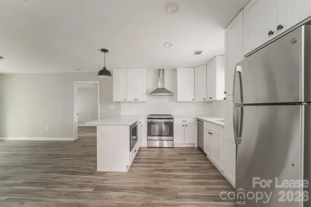a kitchen with a refrigerator a stove top oven and white cabinets
