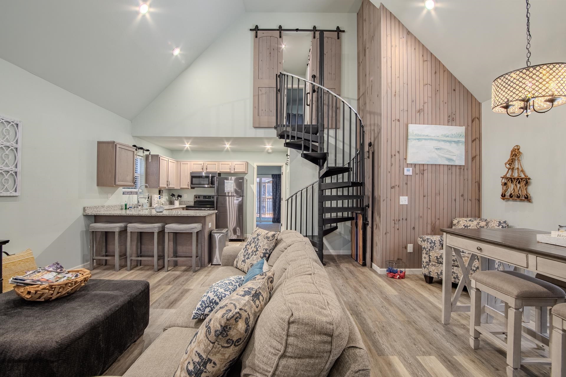 25 Bogey Loop Counce, TN 38326 - Photo 12 of 37 Living area with a barn door, high vaulted ceiling, stairs, light wood finished floors, and wooden walls
