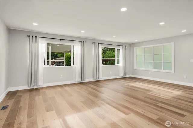 a view of an empty room with a window and wooden floor