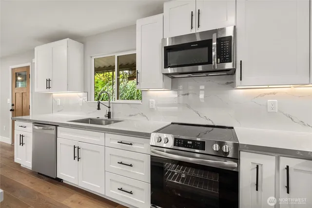 a kitchen with stainless steel appliances a stove a microwave and sink