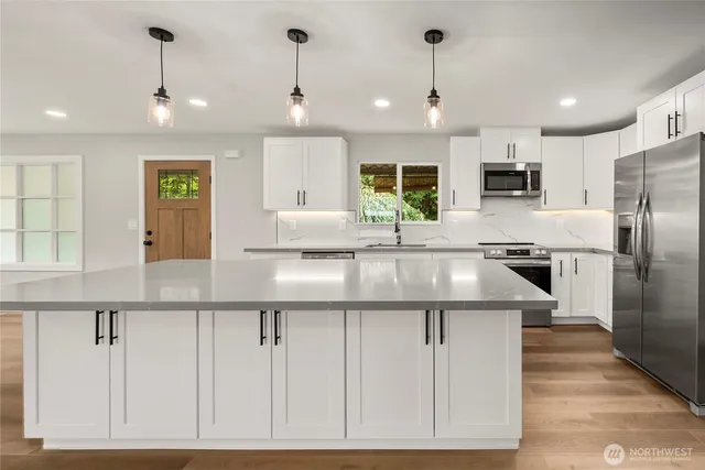 a kitchen with kitchen island granite countertop a sink and refrigerator