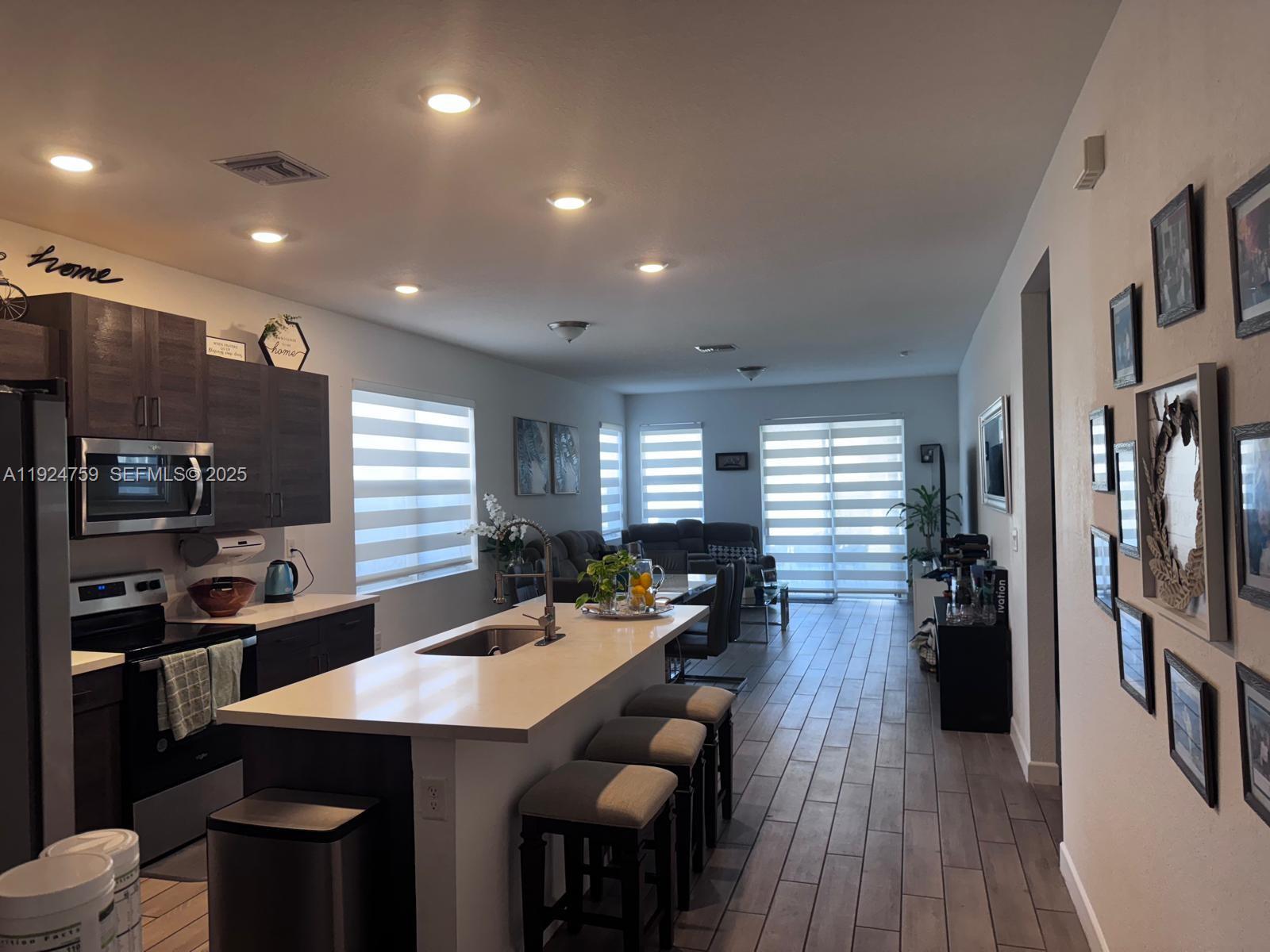 13201 Southwest 269th Terrace Homestead, FL 33032 - Photo 14 of 33 a kitchen with stainless steel appliances a dining table chairs and wooden floor