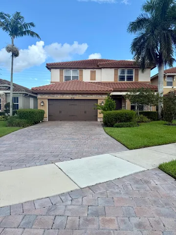 a front view of a house with a yard and potted plants