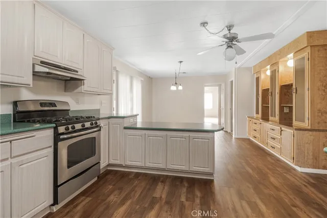 a kitchen with stainless steel appliances granite countertop a stove a sink and white cabinets with wooden floor