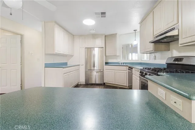 a kitchen with stainless steel appliances granite countertop a stove top oven a sink and a refrigerator