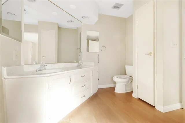 a spacious bathroom with a double vanity sink a mirror and a toilet
