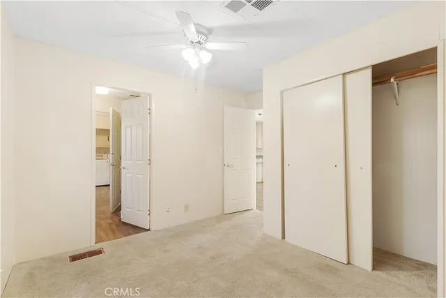 an empty room with closet and a chandelier fan