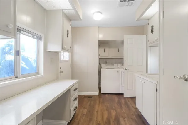 a view of a kitchen with white cabinets and wooden floor