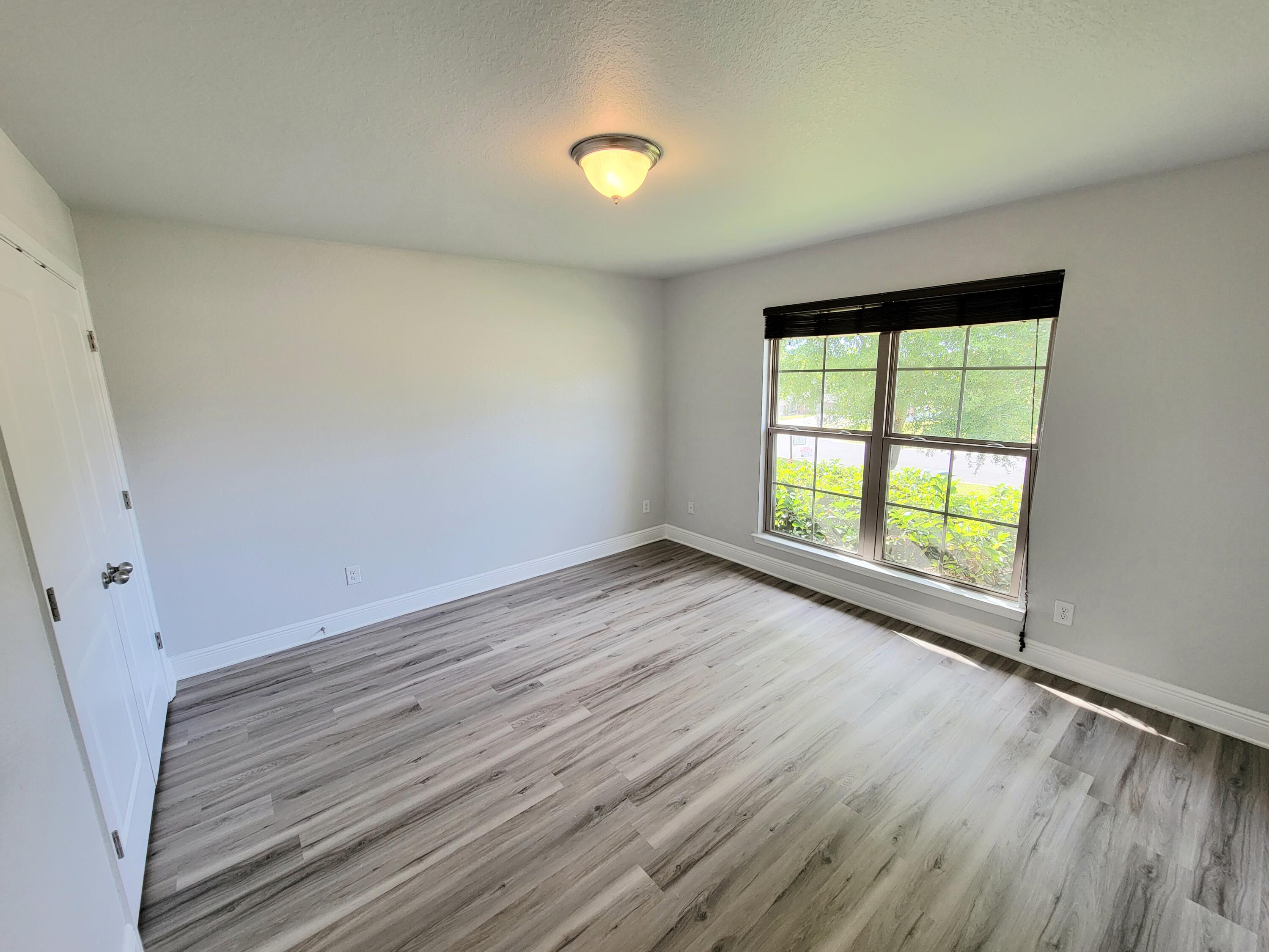 505 Vale Loop Crestview, FL 32536 - Photo 8 of 14 an empty room with wooden floor and windows