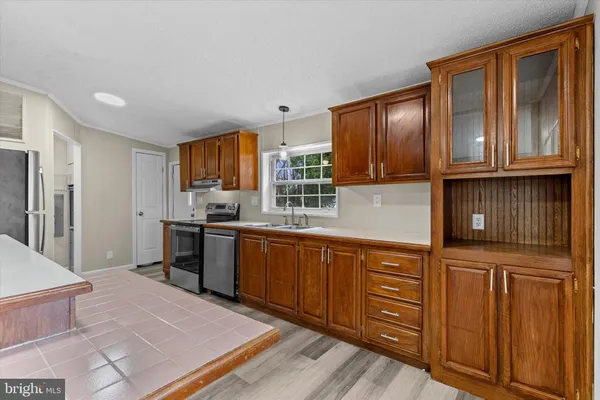 a kitchen with granite countertop wooden cabinets stainless steel appliances a sink and a window