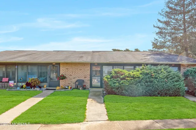 a front view of a house with garden and lots of trees