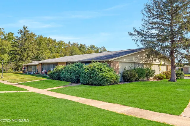 a view of a house next to a big yard and large trees