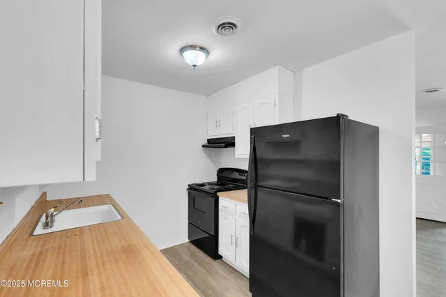 a kitchen with white cabinets and refrigerator