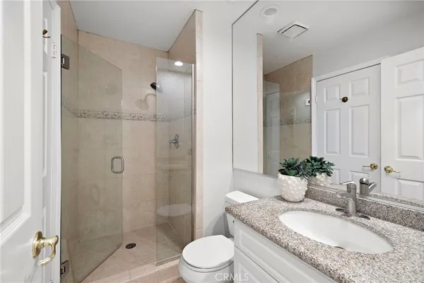 a bathroom with a granite countertop sink toilet a shower and a mirror