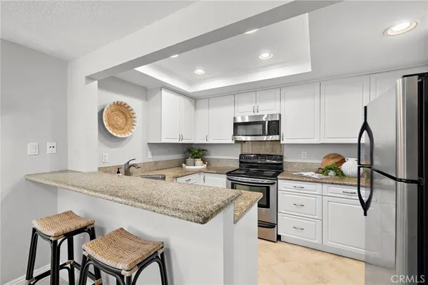 a kitchen with granite countertop a sink stove refrigerator and cabinets