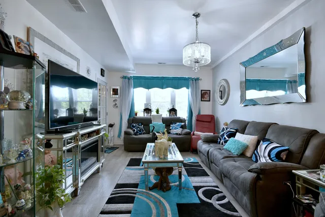 a living room with furniture a flat screen tv and a chandelier