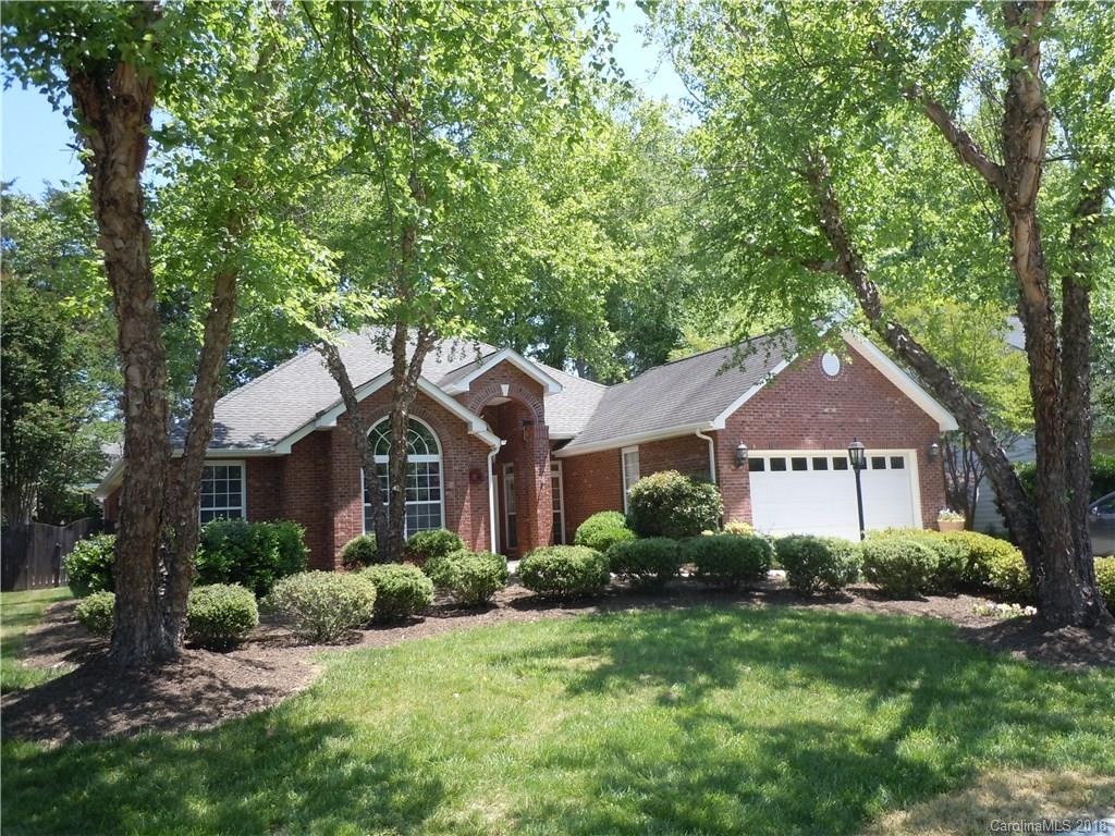 a front view of a house with a yard and large trees