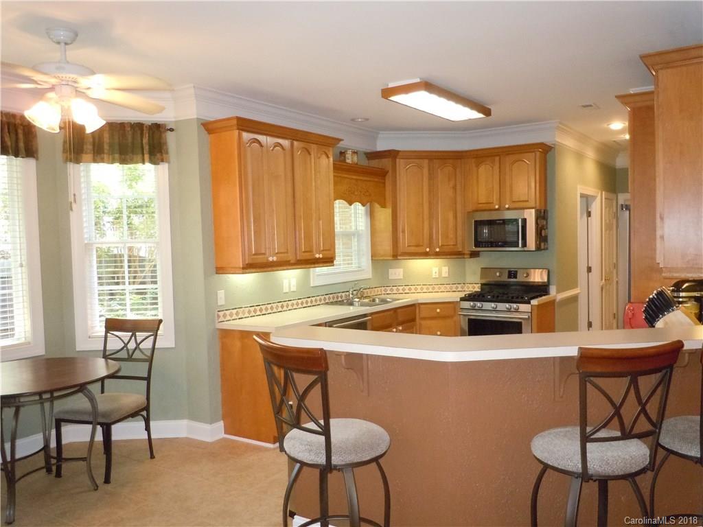 124 Zimmerman Drive Fort Mill, SC 29708 - Photo 16 of 35 a kitchen with stainless steel appliances granite countertop a stove a sink a microwave a dining table and chairs with wooden floor