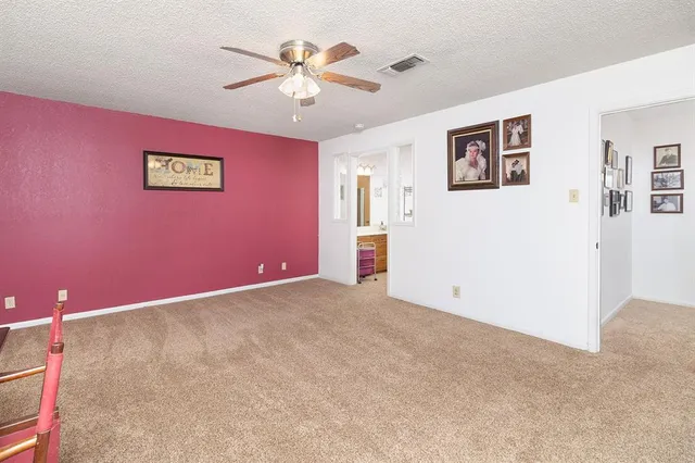a view of an empty room with chandelier fan