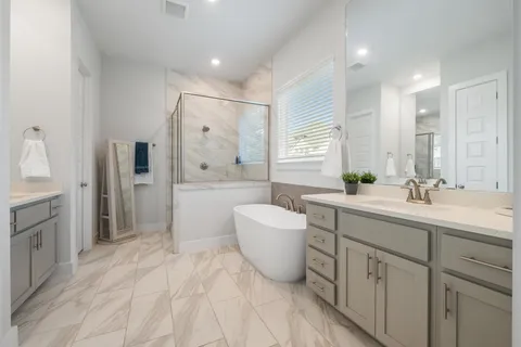 a spacious bathroom with a double vanity sink a mirror a bathtub and window