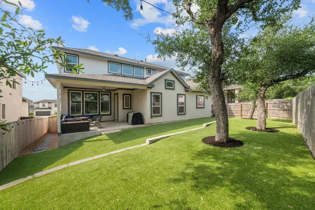 a view of a house with a yard and large tree