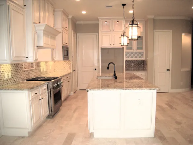 a kitchen with kitchen island granite countertop a sink a counter top space and stainless steel appliances